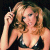 Pixelated image of a person with light brown hair wearing a dark bikini top, holding a cigarette near their face against a dark background.