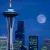 Pixelated static image of a city skyline at night featuring the Space Needle with moon and skyscrapers against blue background