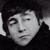 Pixelated grayscale image of a person's face with dark hair, neutral expression, and visible eyes, nose, and mouth against a dark background.