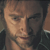 Pixelated close-up of a person's face with light skin tone, visible eyes, nose, mouth, and partial dark hair against a muted background.