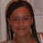 A static pixelated image of a person with dark hair styled in two braids, wearing a light-colored top against a neutral background.