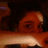 A person's face partially visible behind a horizontal bar, with dark hair and warm lighting.