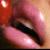 Pixelated close-up of a human eye with pinkish-red and brown tones, showing eyelashes and partial skin texture.