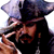 Pixelated static image of a character with long dark hair, wearing a tricorn hat and black clothing, holding an object near their face.
