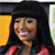 A pixelated portrait of a person with long black hair wearing a red top, smiling against a yellow and gray background.