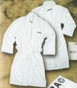 Two white bathrobes with subtle vertical stripes lie on a textured brown surface, one partially overlapping the other.