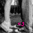 A grayscale image of a figure in a dark outfit with a light-colored column on the left, featuring bright pink '<3' text in the lower right corner.