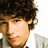 Pixelated close-up of a person with dark curly hair, light skin tone, and visible ear against white background.