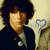 Pixelated image of a person with dark curly hair wearing a dark jacket over light shirt, next to pink and white striped background with text.