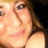 Pixelated close-up of a person's face with light skin tone, brown hair strands visible on the right side, and dark eye makeup around one eye.