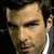 A static image of a man in a dark suit with a white shirt, showing three slightly different facial expressions across a