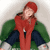 Static 50x50 pixel icon of a person with red hair wearing a long red dress and dark blue pants, seated on green foliage against a light gray background.