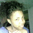 Pixelated static image of a person with dark hair and light skin, wearing a white top against a greenish background.