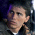 Pixelated close-up of a person's face with dark hair, wearing a dark jacket over a white shirt, against a dark background with purple and blue tones.