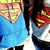 A blue-shirted character with a yellow emblem on chest, red shoulder accents, and black pants, shown in two slightly different poses with visible pixelation.
