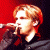 A pixelated split-screen image showing a person singing into a microphone on the left and green text reading "Original Icons .com" on the right against a dark background.