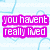 Pixelated text in bright pink letters on a light blue background with faint heart outlines, displaying the phrase "you havent really lived until you've met someone who is worth dying for.".