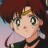 Pixelated close-up of a character with large eyes, light skin, and brown hair, wearing a dark outfit with a white collar against a blurred background.