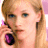 A pixelated close-up of a person with light brown hair holding a dark purple object near their mouth against a pink and white background.