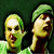Pixelated static image of two cartoonish humanoid figures with green skin tones against a dark background, one wearing a green cap and the other bald, both with exaggerated facial features.