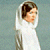 Static pixelated image of a person in white attire with a head covering against a muted background.