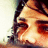 Pixelated close-up of a person's face with dark hair, warm skin tones, and visible eye details against a light background.