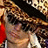 A pixelated image of a person with curly brown hair wearing sunglasses and a patterned jacket, next to yellow text on purple background reading 'that's mah boy'.