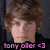 Pixelated portrait of a person with brown curly hair, light skin, and purple eyes, wearing a black top against a dark background with pink text reading 'tony olcr <3' at the bottom.