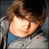 A person with brown hair and blue eyes wears a gray jacket over a blue shirt, with a red heart symbol changing shape on the jacket.