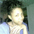 Pixelated static image of a person with light skin tone wearing blue clothing against dark and green background.