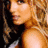A pixelated image of a woman with light brown hair and shoulder-length waves, wearing a sleeveless top against a black background.