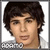 Static pixelated image of a person with dark curly hair, light skin tone, and neutral expression wearing a checkered shirt against white background.
