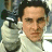 A pixelated image shows a person in a light-colored shirt holding a dark camera with a white flash attachment, positioned near their shoulder.