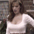 A woman with long brown hair wearing a white low-cut top stands against a blurred background, next to green text reading "Original Icons .com" in pixelated font.