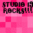 Pixelated pink checkered background with repeated black text 'STUDIO 19 ROCKS!!!' in two