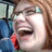 Pixelated image of a person with light brown hair and glasses laughing, surrounded by black background with pixelated text.