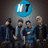 Four individuals in dark clothing stand beneath a blue circular logo with white 'NT' text, while pixelated blue text reads 'kevin travis', 'jj', and 'v' on black backgrounds.