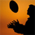 Pixelated orange and black icon depicting a stylized running figure with an oval head, likely representing a sports mascot or character.