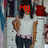 A static image of a person in a white sleeveless top and dark pants with pink waistband, standing against a background of clothing racks.