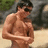 A pixelated image shows a shirtless person standing outdoors with arms crossed, next to a bright pink background displaying text.