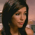 A pixelated close-up of a person with dark hair, light skin, and a neutral expression, wearing a dark sleeveless top against a blurred background.