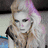 A pixelated image of a person with blonde hair and blue eyes, wearing dark clothing with light trim.