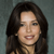 A static pixelated image of a person with long dark hair, light skin, and a neutral expression against a muted gray background.