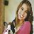 A pixelated static image shows a person with long brown hair wearing a pink top, holding a small black-and-white dog against an indoor background.