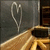 A heart-shaped wireframe icon with a golden-brown curved base against a dark gray background.