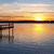 Sunset over water with a pier, showing subtle color shifts across four