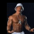 Pixelated image of a shirtless man wearing white shorts and a white cap, standing against a dark background with one arm extended.