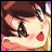 Anime-style character face with brown hair, large dark eyes, red cheeks, and a small open mouth, next to pixelated text on black background.