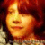 Pixelated close-up of a person's face with warm orange and red tones, showing closed eyes and a slight smile against a dark background.