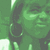 Green-tinted pixelated image of a person with large hoop earrings, smiling face, and dark hair in two overlapping